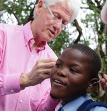 Bill Clinton fitting a child with hearing aids